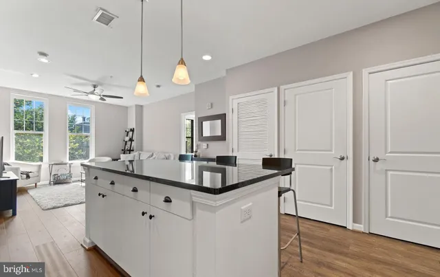 a very nice looking kitchen with granite countertop a stove oven a sink dishwasher a dining table and chairs with wooden floor