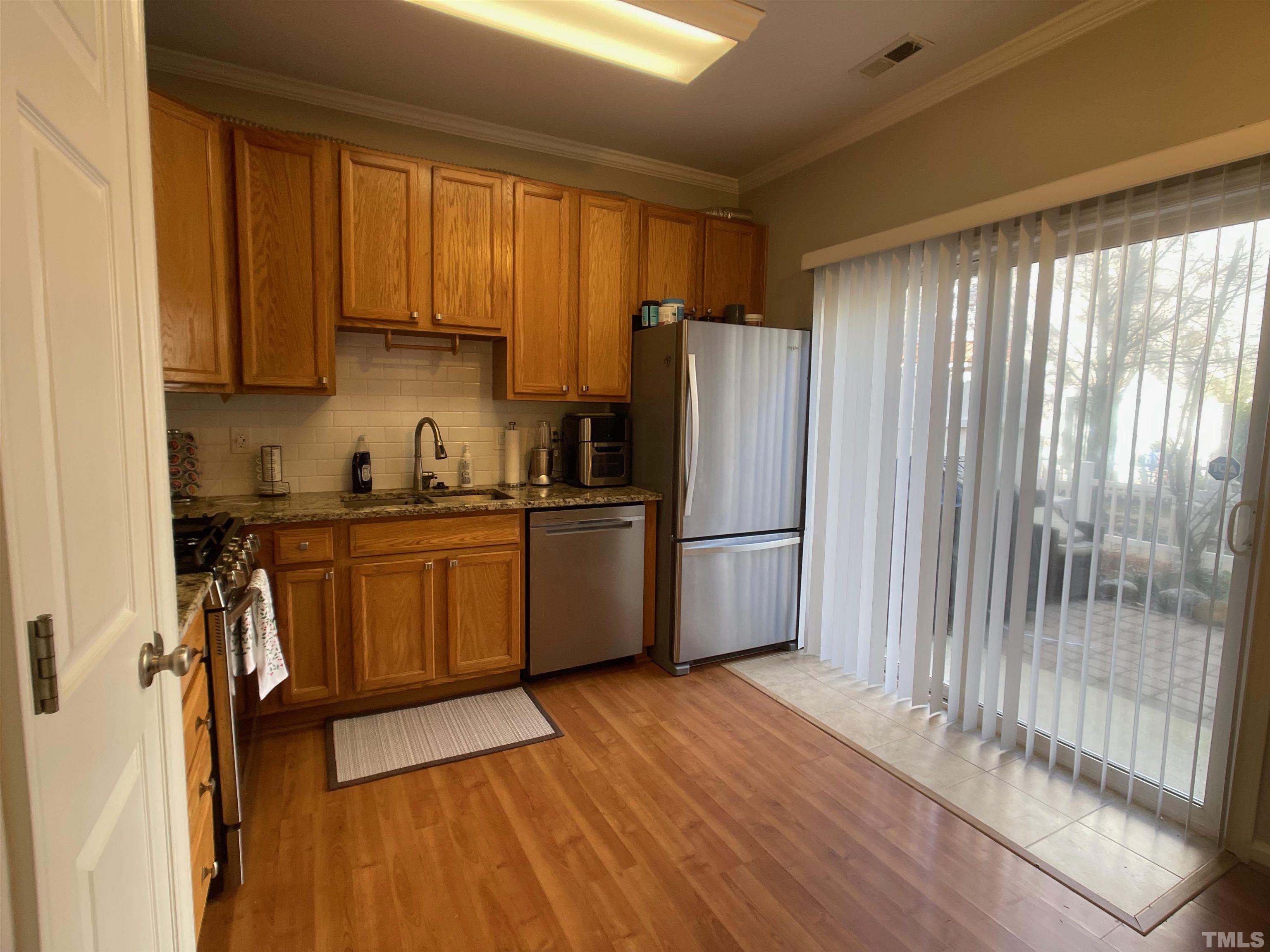 11710 Mezzanine Drive, Unit 101 Raleigh, NC 27614 - Photo 7 of 23 a kitchen with granite countertop a refrigerator a sink a stove and white cabinets with wooden floor