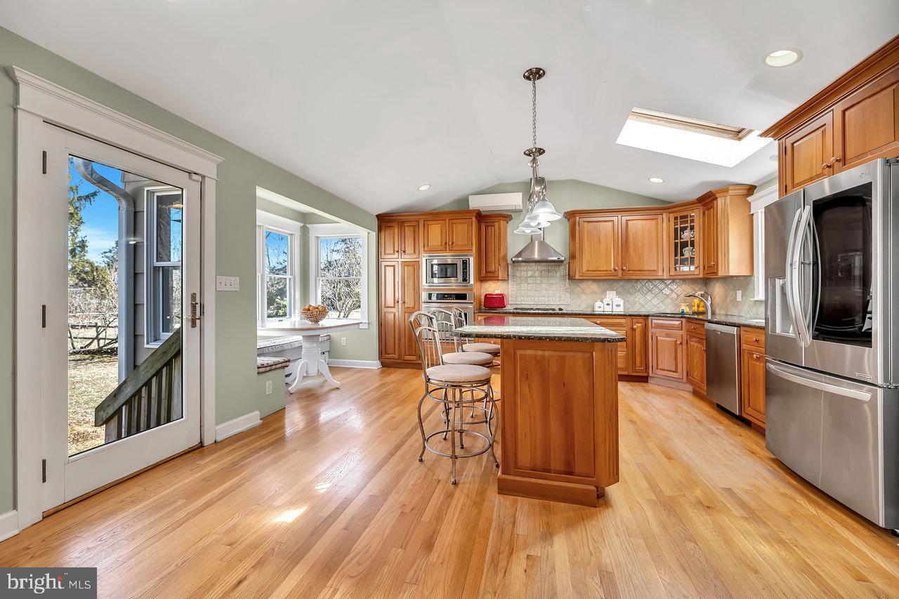 23 Griggs Road Cranbury, NJ 08512 - Photo 15 of 40 a kitchen with stainless steel appliances wooden floor dining table and chairs