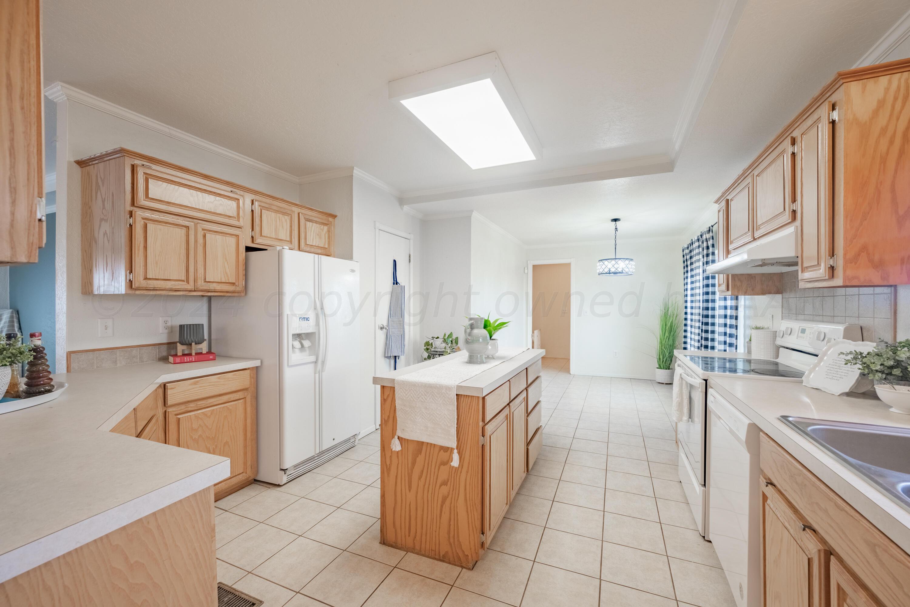 8701 Foxtail Street Amarillo, TX 79118 - Photo 11 of 33 a kitchen with stainless steel appliances granite countertop a stove top oven a sink a refrigerator white cabinets and wooden floor