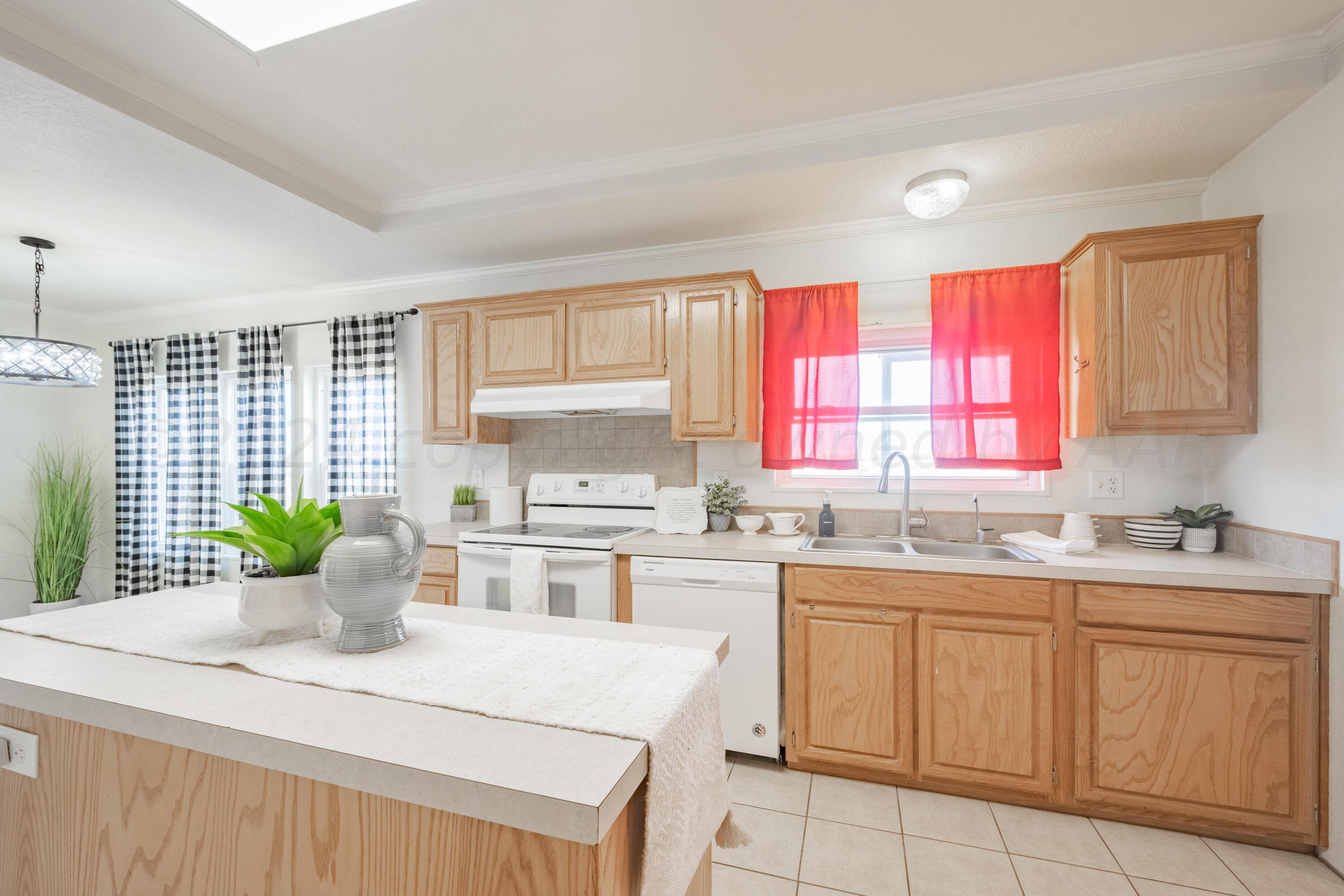 8701 Foxtail Street Amarillo, TX 79118 - Photo 13 of 33 a kitchen with a stove a sink a cabinets and wooden floor
