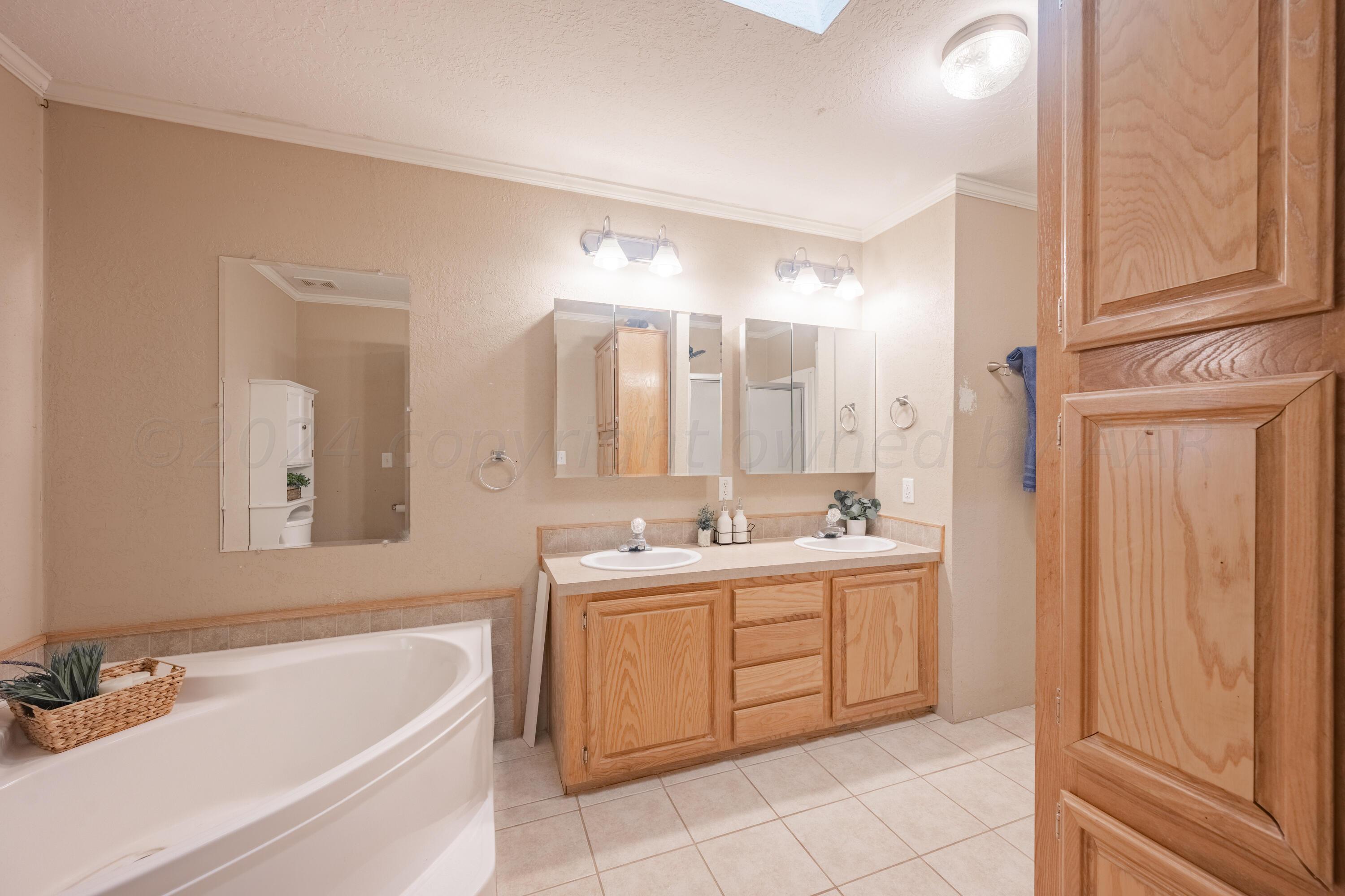 8701 Foxtail Street Amarillo, TX 79118 - Photo 17 of 33 a bathroom with a tub a sink and mirror
