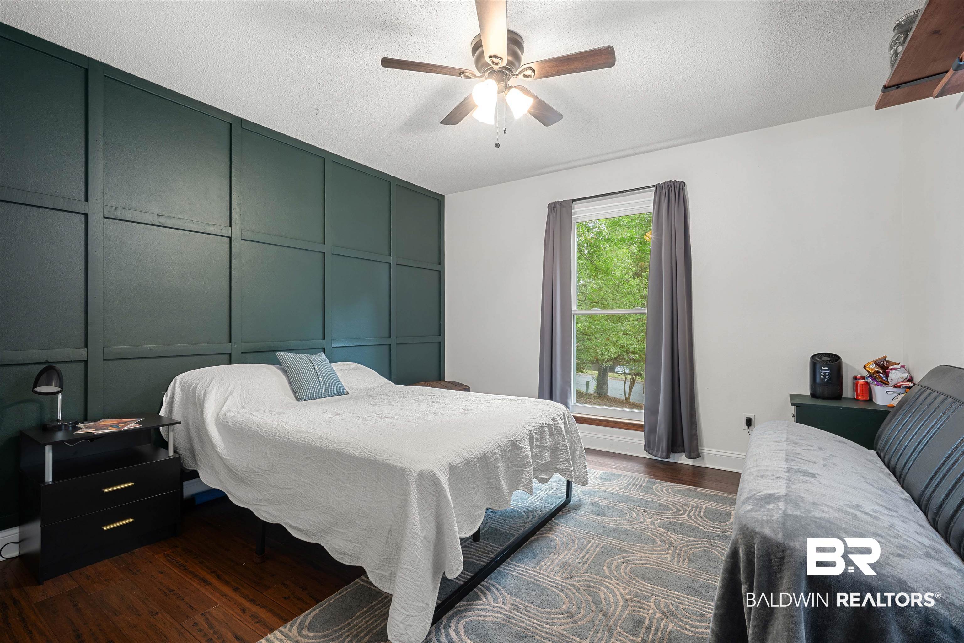 71 Caisson Trace Daphne, AL 36527 - Photo 20 of 36 Accent wall with dark green paneling, wood-finish flooring, and a ceiling fan with integrated lighting