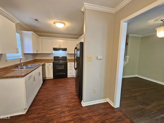 a kitchen with granite countertop a refrigerator stove and sink