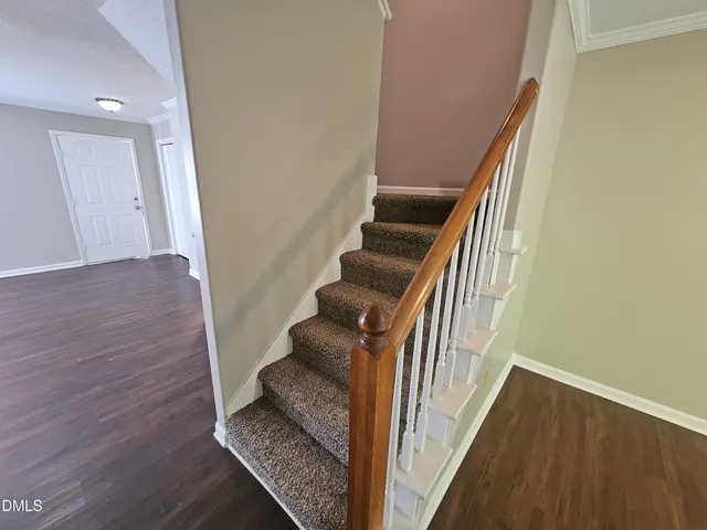 a view of a hallway with wooden floor and staircase