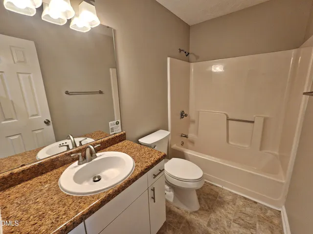 a bathroom with a granite countertop sink a toilet a mirror and shower