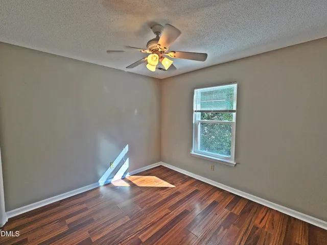a view of an empty room with window and wooden floor