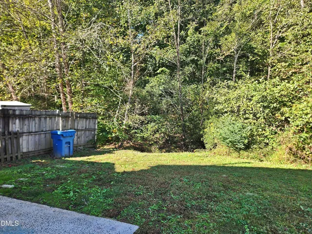 a view of yard with small cabin and wooden fence