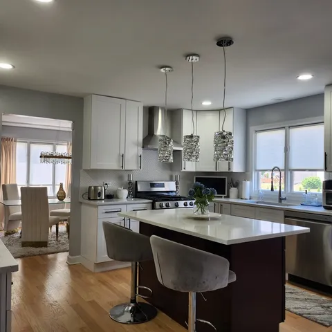 a kitchen with kitchen island granite countertop a sink a stove a refrigerator and a dining table with wooden floor