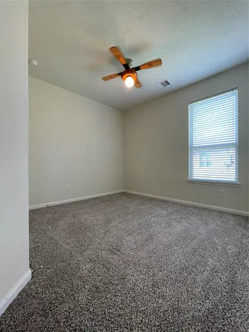 an empty room with windows and ceiling fan