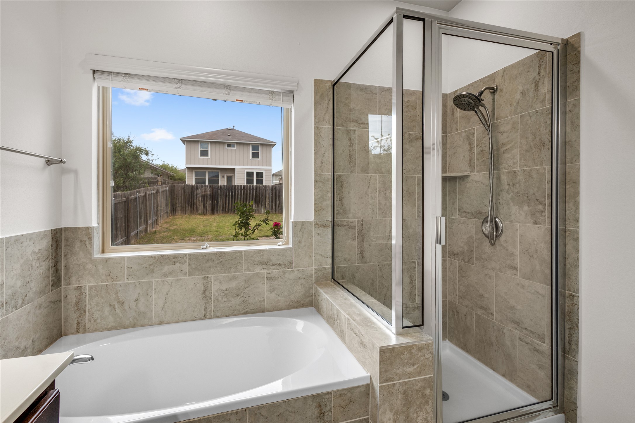 397 Limerick Road Buda, TX 78610 - Photo 18 of 33 The separate walk-in shower is finished with oversized tile in an earthy stone pattern, featuring a modern glass enclosure that keeps the bathroom feeling open and bright.