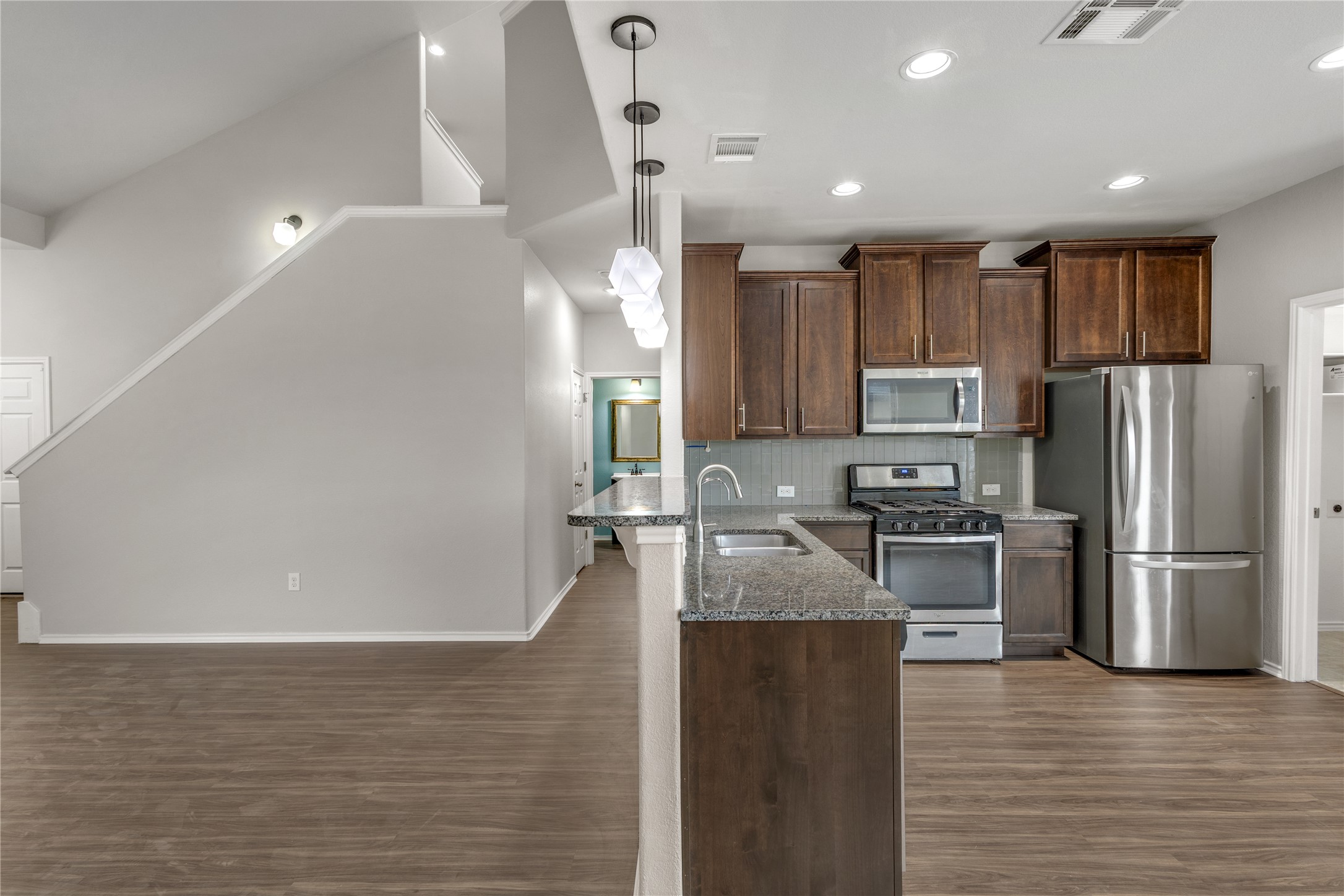 397 Limerick Road Buda, TX 78610 - Photo 7 of 33 Three geometric pendant lights hang above the counter, adding a touch of style and cast a warm glow over the kitchen.