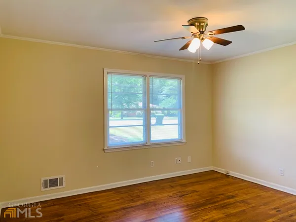 an empty room with wooden floor and windows