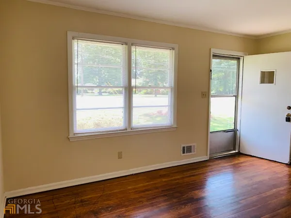 a view of an empty room with wooden floor and a window