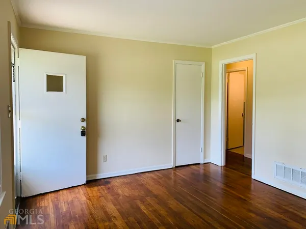 a view of an empty room with wooden floor and a window