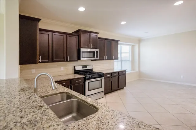 a kitchen with kitchen island granite countertop a sink stove top oven and cabinets