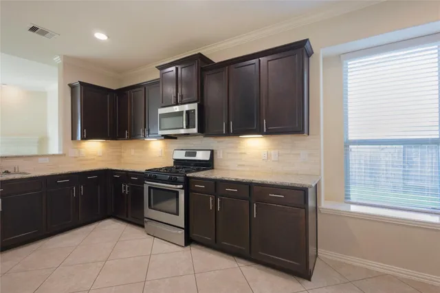 a kitchen with stainless steel appliances granite countertop wooden cabinets a stove top oven and a sink