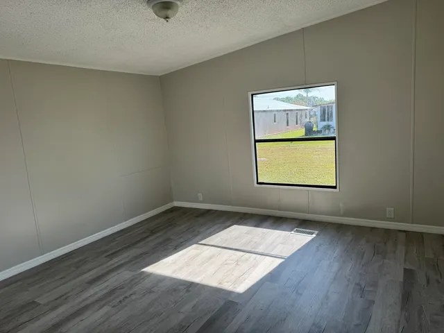 an empty room with wooden floor cabinet and windows