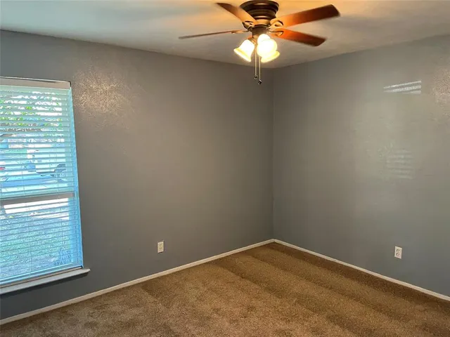 an empty room with a window and ceiling fan