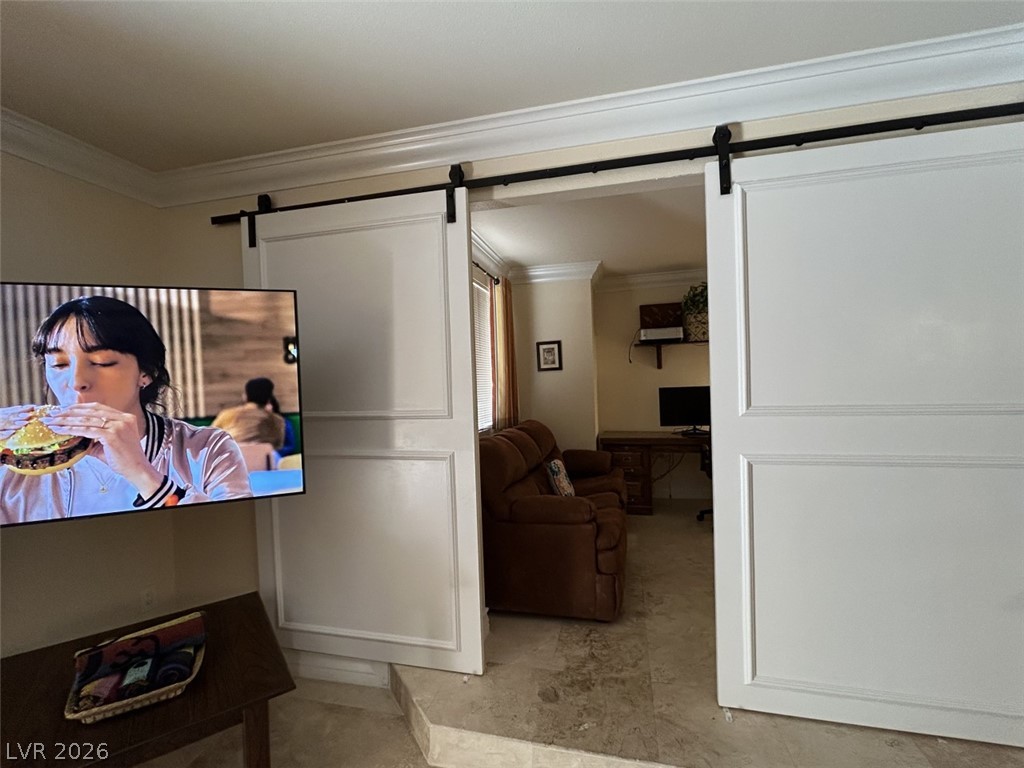 210 East Flamingo Road, Unit 137 Las Vegas, NV 89169 - Photo 10 of 32 Sliding barn doors elegantly open to a cozy den with rich crown molding and textured flooring.