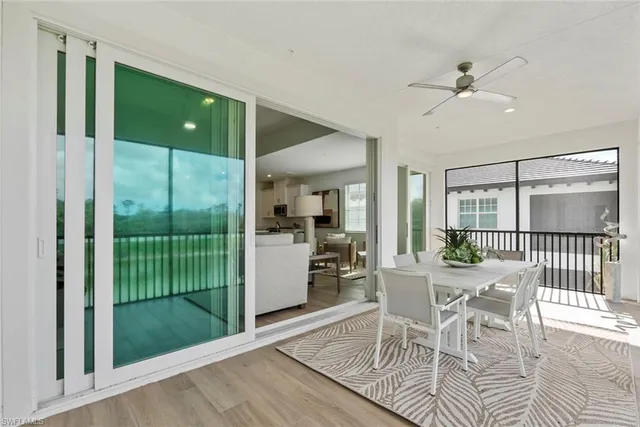 a dining room with wooden floor a chandelier fan windows and a table