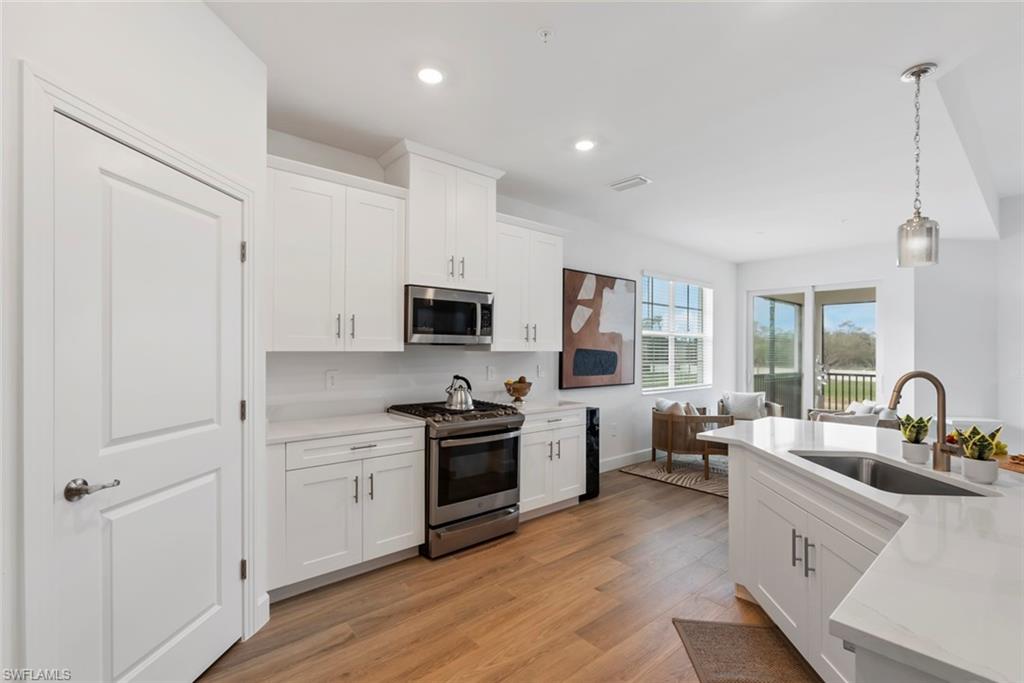 16889 Fairgrove Way, Unit 5201 Naples, FL 34110 - Photo 6 of 28 a kitchen with white cabinets and stainless steel appliances