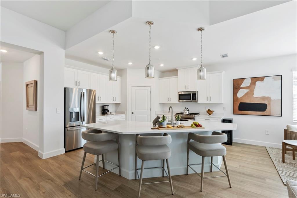 16889 Fairgrove Way, Unit 5201 Naples, FL 34110 - Photo 8 of 28 a kitchen with stainless steel appliances kitchen island granite countertop a dining table chairs and a refrigerator a sink