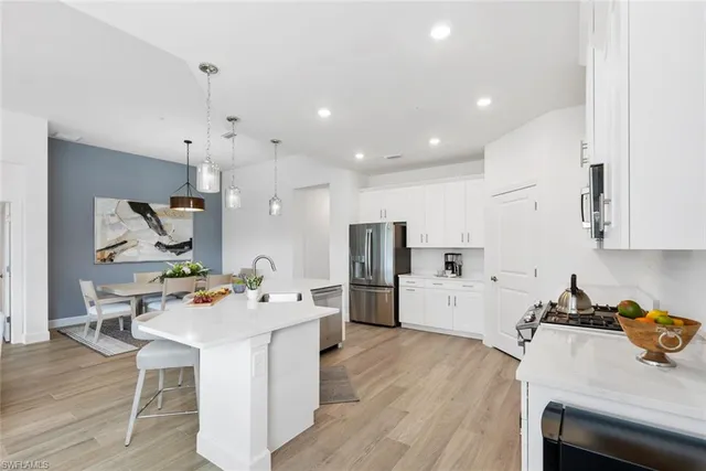 a room with stainless steel appliances kitchen island a table and chairs in it