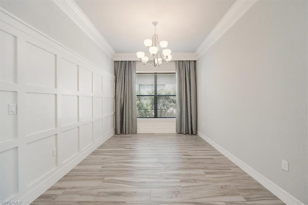 13418 Silktail Drive Naples, FL 34109 - Photo 18 of 36 a view of a chandelier in an empty room with wooden floor