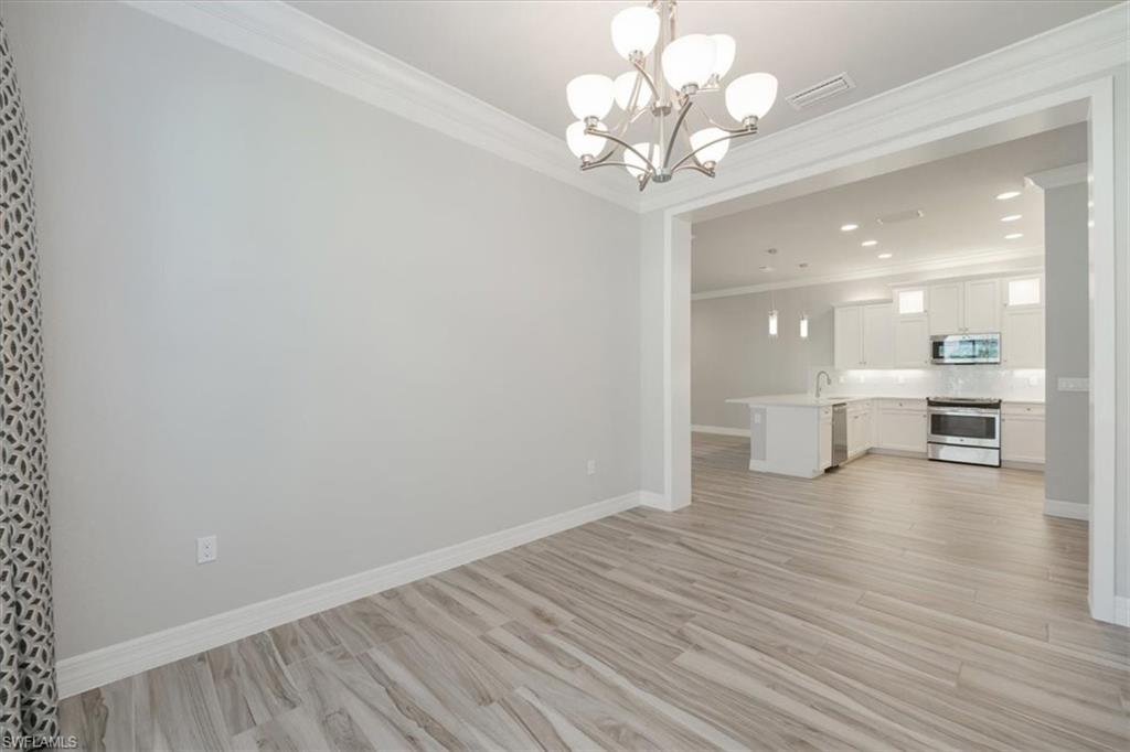 13418 Silktail Drive Naples, FL 34109 - Photo 19 of 36 a view of a room with wooden floor and windows