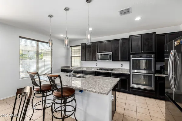 a kitchen with a stove a refrigerator and chairs