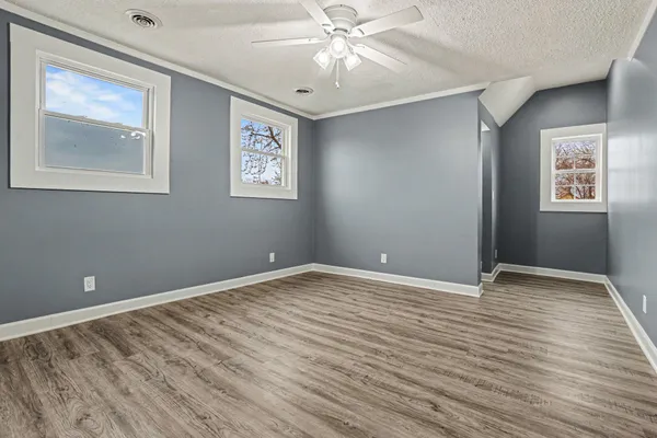 a view of an empty room with window and wooden floor