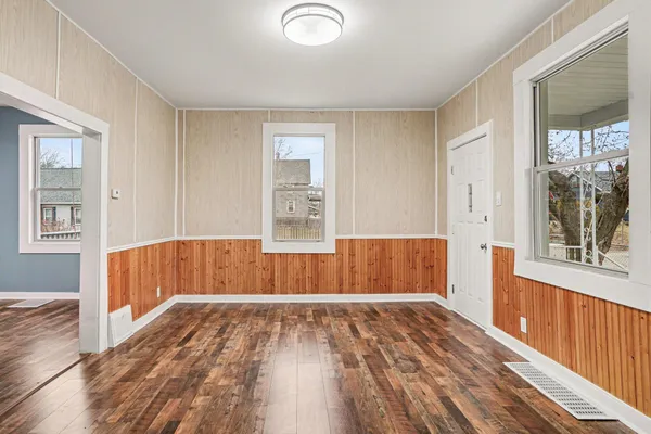 a view of an empty room with wooden floor and a window