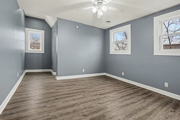 a view of an empty room with wooden floor and a chandelier