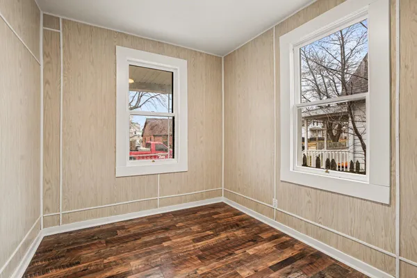a view of an empty room with a window and wooden floor