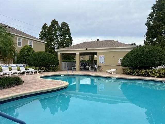 a view of a swimming pool with couches chairs under an umbrella
