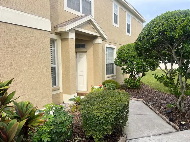 a view of a white house with a small yard and plants