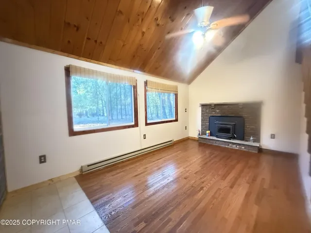 an empty room with wooden floor fireplace and windows