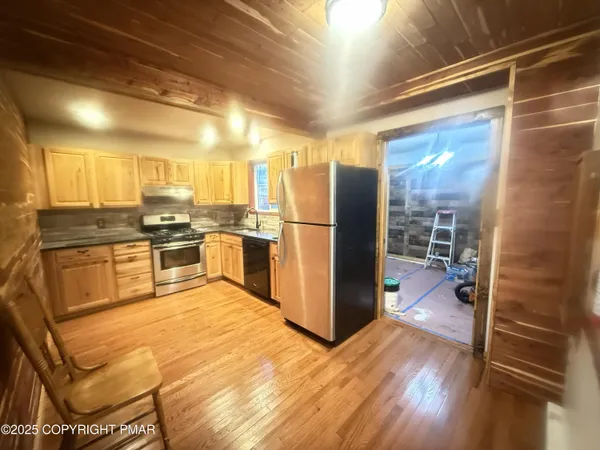 a kitchen with stainless steel appliances granite countertop a refrigerator a stove and a wooden floors