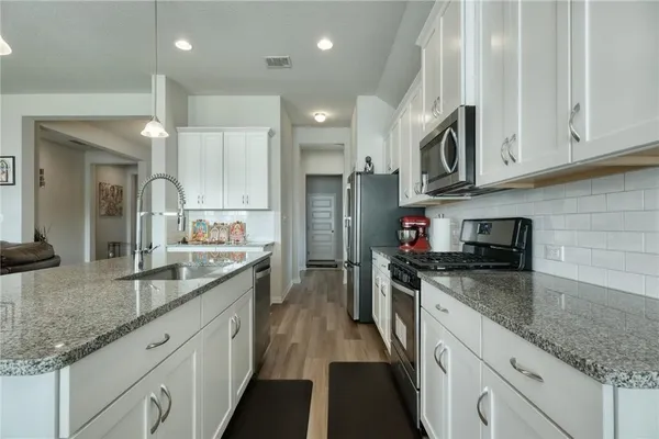 a kitchen with stainless steel appliances granite countertop a sink stove and refrigerator