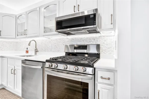 a kitchen with stainless steel appliances a stove a microwave a sink and cabinets
