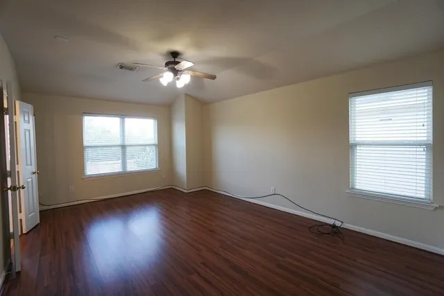 a view of an empty room with wooden floor and a window