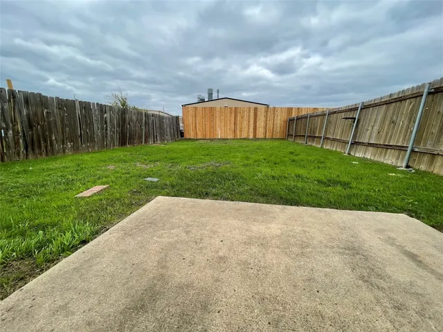 a view of backyard with barbeque grill and wooden fence