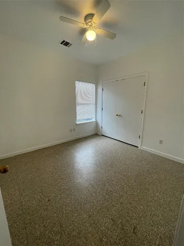 an empty room with a fan & a window