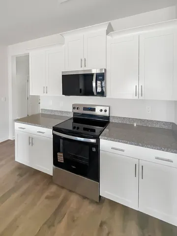 a large kitchen with granite countertop a sink a counter space stainless steel appliances and cabinets