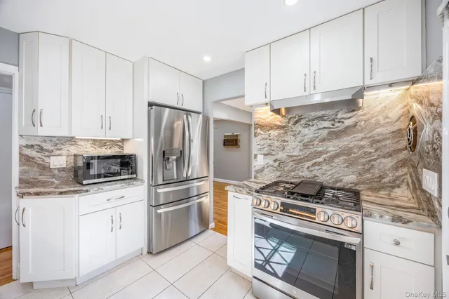 a kitchen with white cabinets and stainless steel appliances