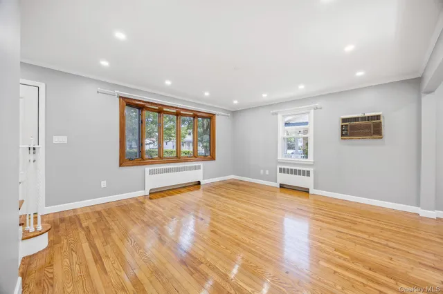 a view of an empty room with window and wooden floor