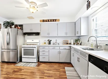 a kitchen with stainless steel appliances white cabinets a sink and a refrigerator