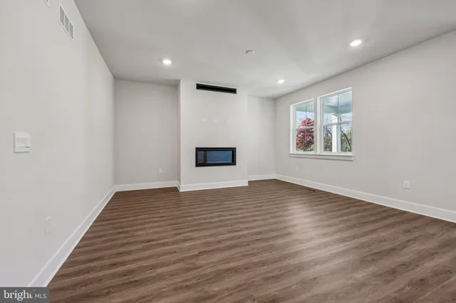 a view of empty room with wooden floor and fireplace