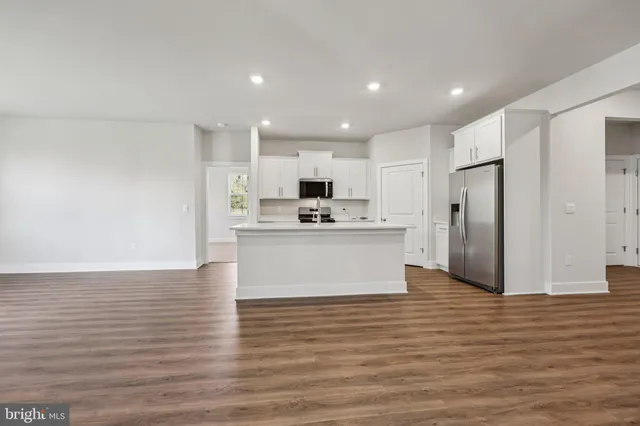 a view of kitchen with granite countertop refrigerator oven a sink and white cabinets with wooden floor